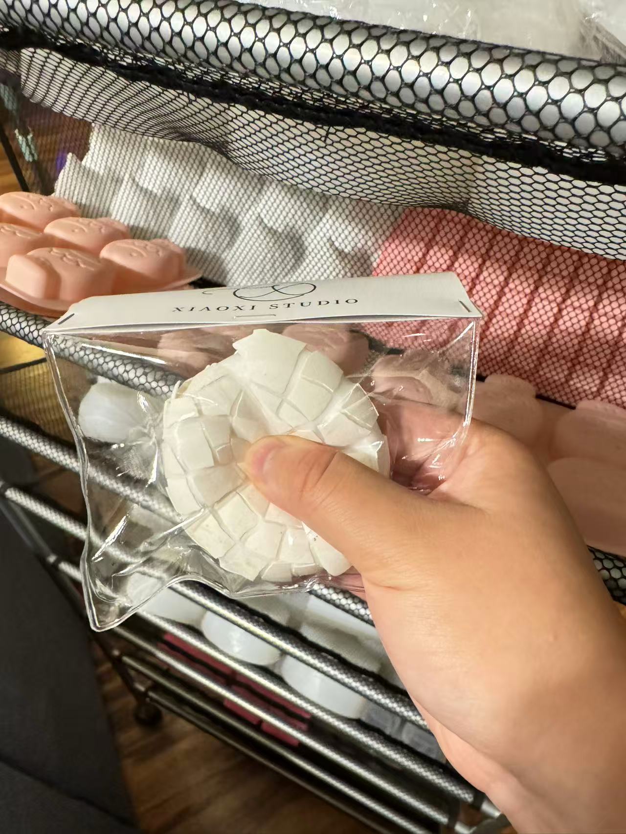 A hand squeezing a silicone-filled eggshell inside clear packaging